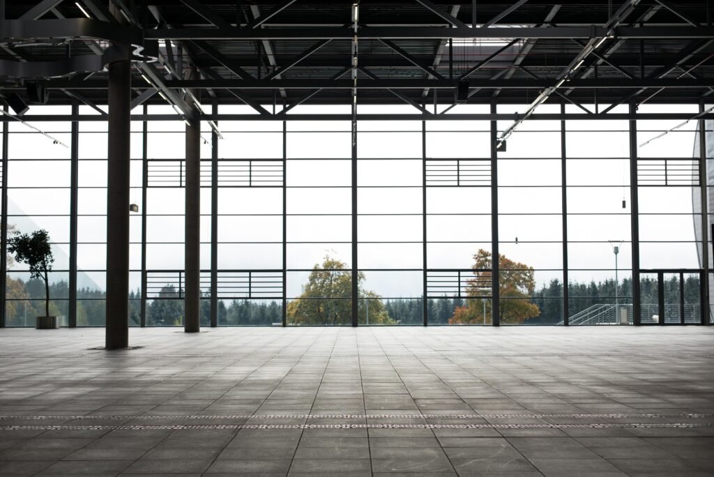 Modern industrial 3d interior with floor-to-ceiling windows, tiled flooring, and a scenic view of trees—blending natural light with contemporary 3d design.